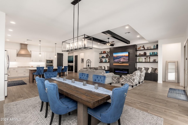 dining space with ceiling fan, beamed ceiling, and light hardwood / wood-style floors