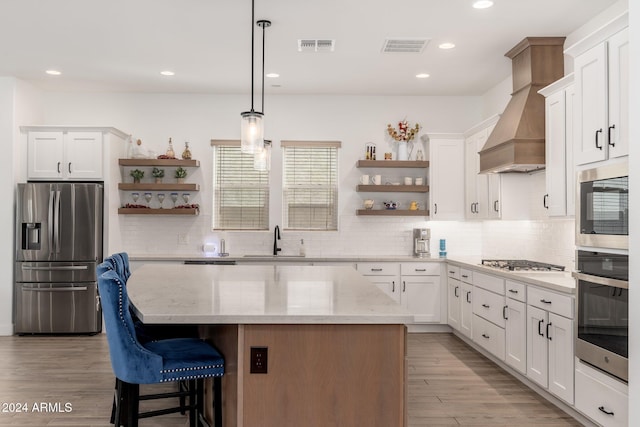 kitchen featuring appliances with stainless steel finishes, light hardwood / wood-style flooring, white cabinetry, and a kitchen island