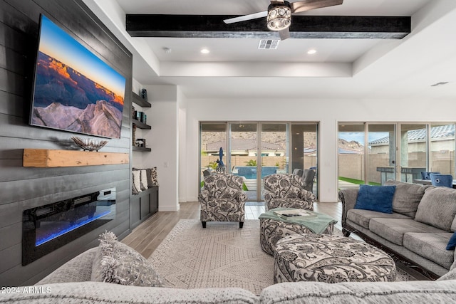 living room with ceiling fan, light hardwood / wood-style flooring, and beamed ceiling