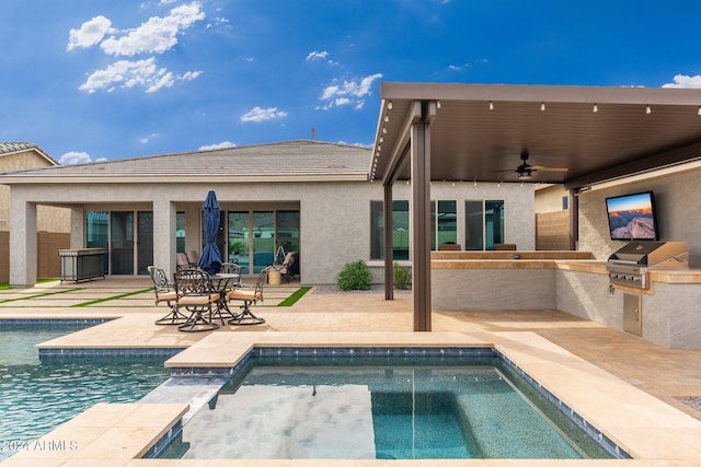 rear view of property featuring a jacuzzi, an outdoor kitchen, ceiling fan, and a patio area