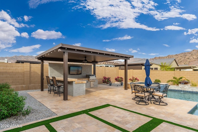 view of patio / terrace featuring area for grilling, exterior bar, pool water feature, ceiling fan, and a fenced in pool