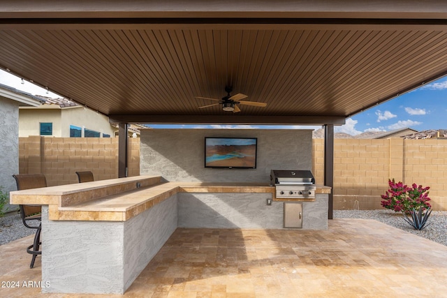 view of patio / terrace featuring grilling area, ceiling fan, exterior bar, and exterior kitchen