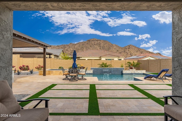 view of pool featuring pool water feature, a mountain view, and a patio