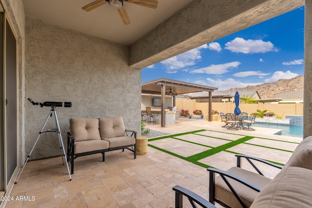 view of patio featuring area for grilling, exterior bar, ceiling fan, a mountain view, and a fenced in pool