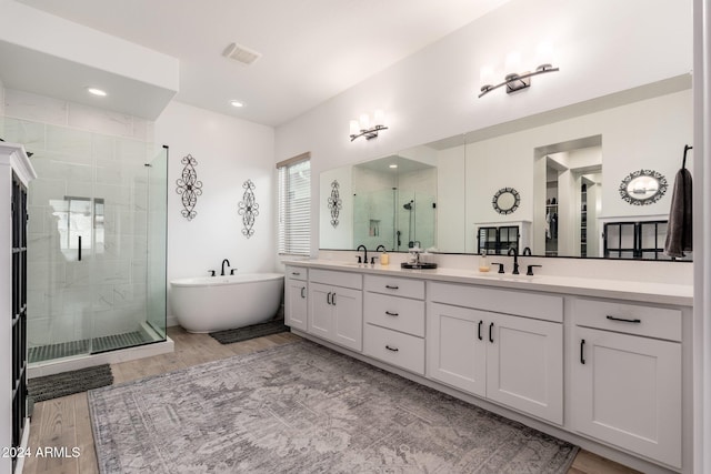 bathroom featuring plus walk in shower, hardwood / wood-style floors, and vanity