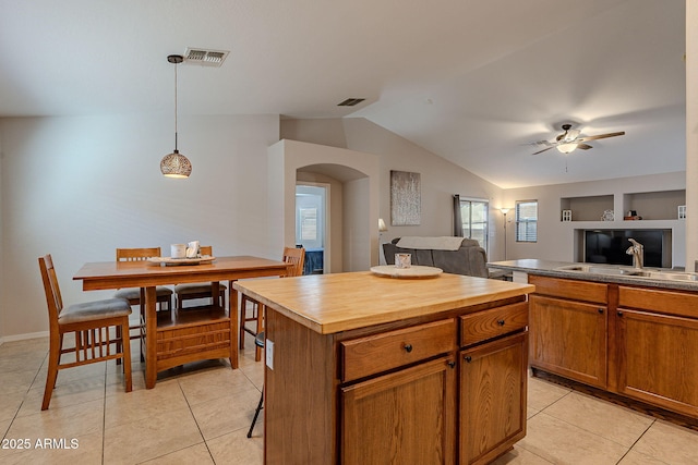 kitchen featuring light tile patterned flooring, lofted ceiling, decorative light fixtures, and a kitchen island