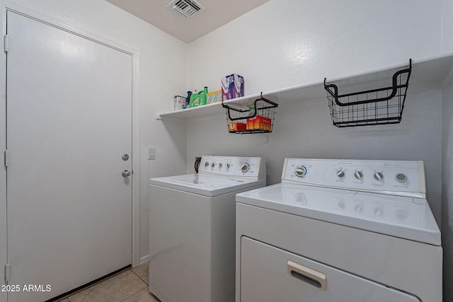 clothes washing area featuring washing machine and clothes dryer and light tile patterned floors