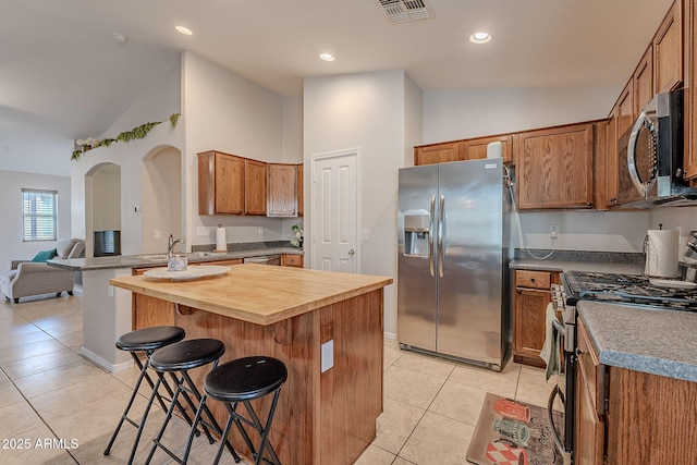 kitchen featuring light tile patterned floors, sink, stainless steel appliances, a center island, and a kitchen bar