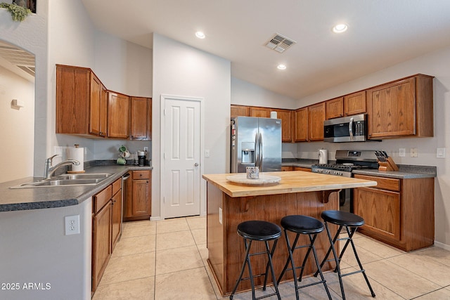 kitchen featuring a kitchen island, appliances with stainless steel finishes, sink, a breakfast bar area, and light tile patterned floors