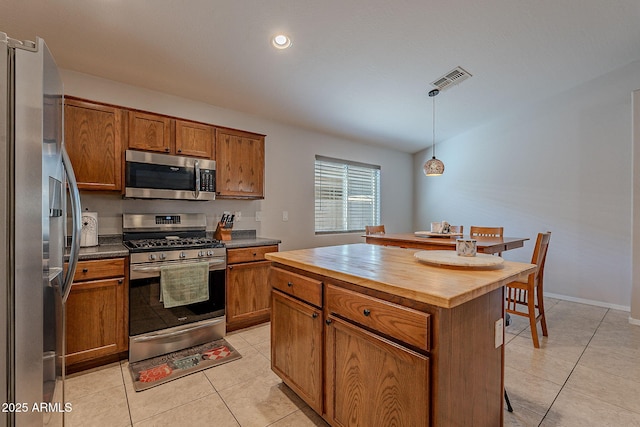 kitchen with hanging light fixtures, appliances with stainless steel finishes, a center island, and light tile patterned floors