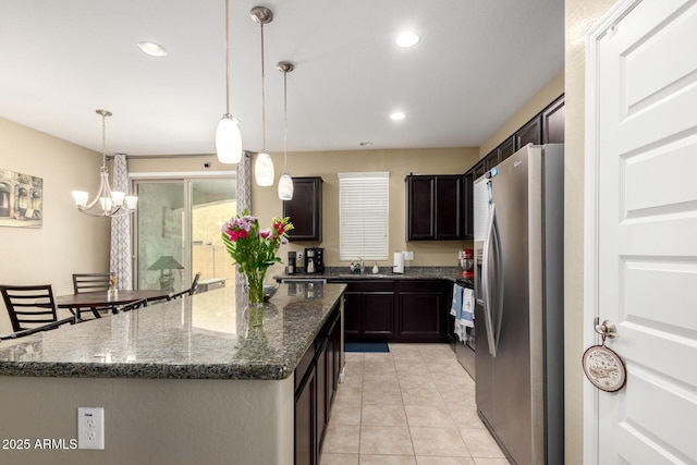 kitchen with a kitchen island, stainless steel fridge, recessed lighting, a sink, and dark stone countertops