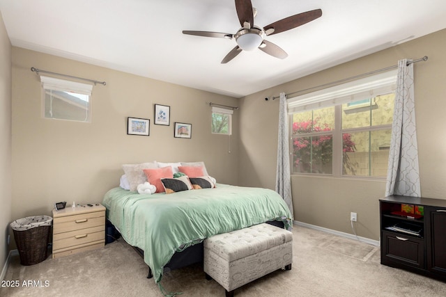 bedroom with baseboards, light colored carpet, multiple windows, and ceiling fan