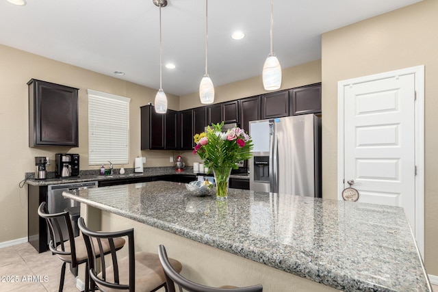 kitchen with a breakfast bar, light stone countertops, baseboards, appliances with stainless steel finishes, and decorative light fixtures