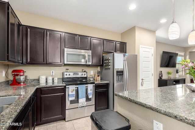 kitchen featuring dark brown cabinetry, light tile patterned flooring, stone countertops, decorative light fixtures, and stainless steel appliances