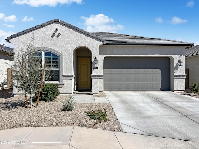 view of front facade with a tile roof, a garage, driveway, and stucco siding