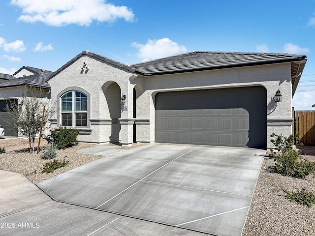 view of front of house featuring stucco siding, a tile roof, fence, concrete driveway, and an attached garage