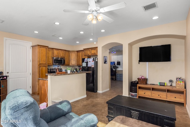 kitchen with ceiling fan, stainless steel appliances, a kitchen island, and dark stone countertops