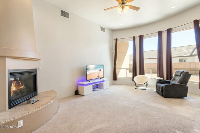 sitting room featuring a large fireplace, a ceiling fan, visible vents, and carpet flooring
