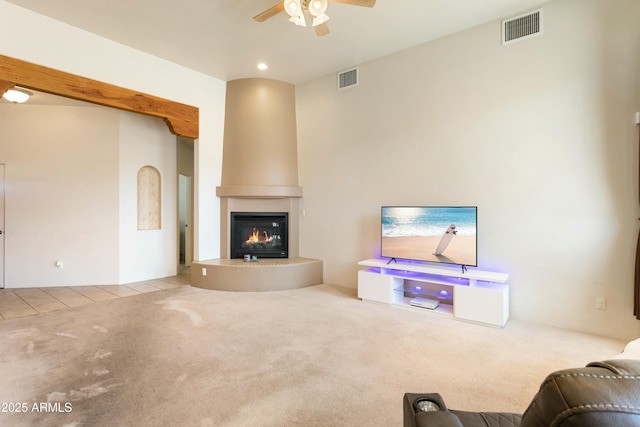 living room featuring light carpet, light tile patterned floors, ceiling fan, and visible vents