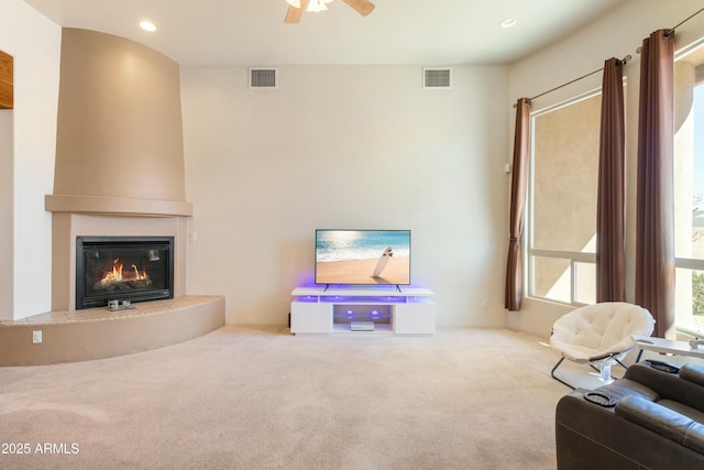 living area featuring a glass covered fireplace, visible vents, carpet flooring, and recessed lighting