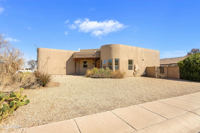 view of front of home featuring fence, a gate, and stucco siding