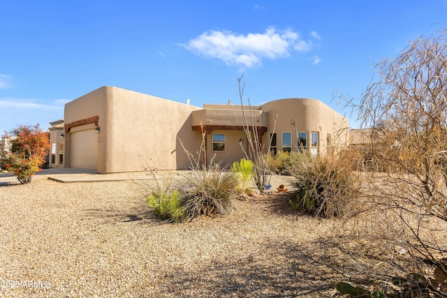 adobe home with a garage and stucco siding