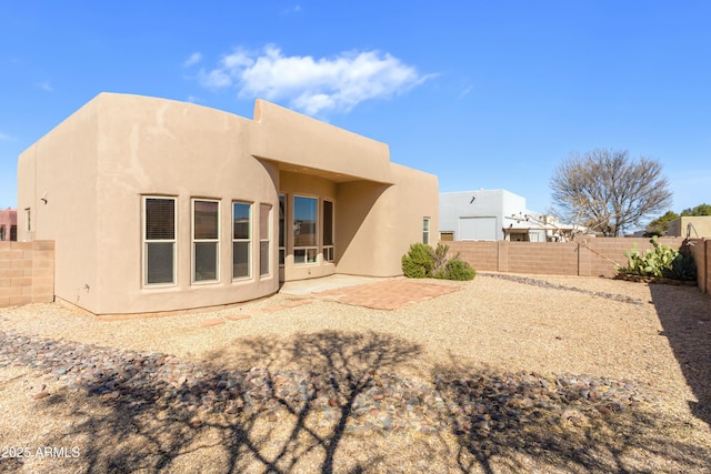 rear view of house featuring a patio area, a fenced backyard, and stucco siding