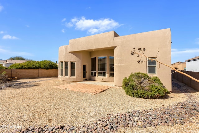 rear view of house featuring a patio area, a fenced backyard, and stucco siding