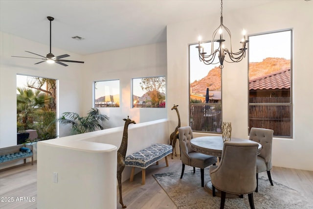 dining room with ceiling fan with notable chandelier and light wood-type flooring