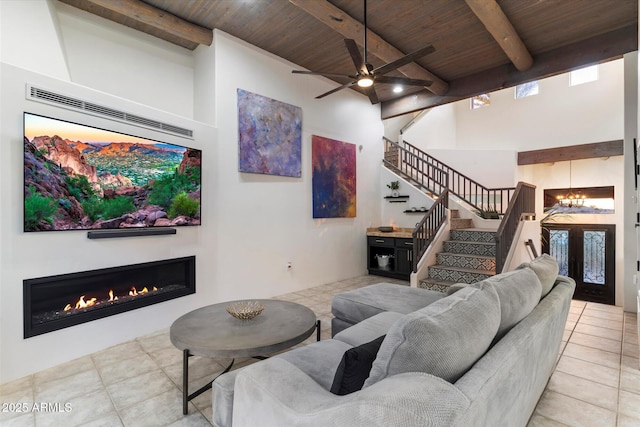 living room featuring beamed ceiling, light tile patterned flooring, ceiling fan with notable chandelier, and wood ceiling