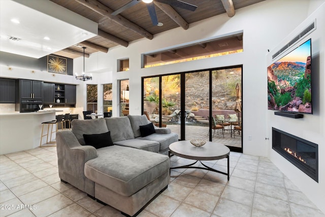 tiled living room featuring wood ceiling, a towering ceiling, ceiling fan with notable chandelier, and beamed ceiling