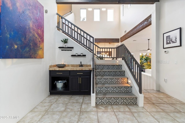 stairway featuring tile patterned floors, sink, and a high ceiling