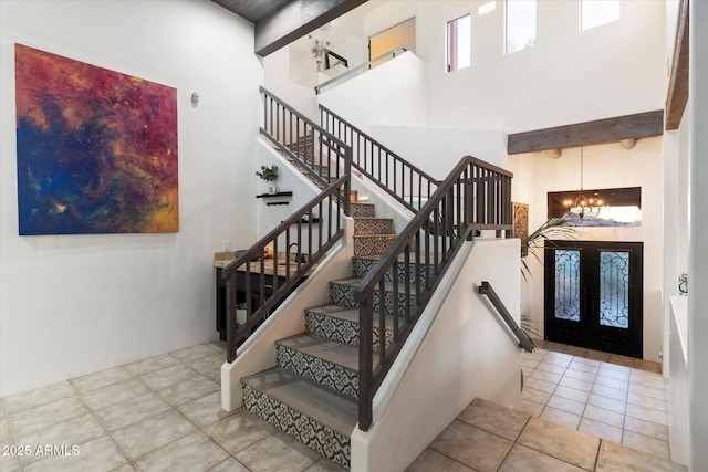 staircase with a high ceiling, tile patterned flooring, and a chandelier