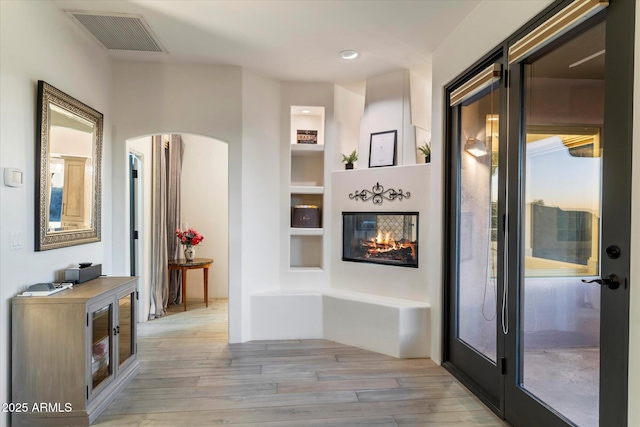 hall featuring built in shelves and light hardwood / wood-style floors