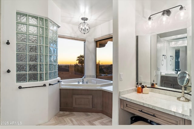 bathroom with vanity, a tub to relax in, a notable chandelier, and parquet flooring