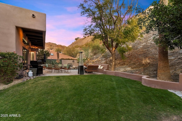 yard at dusk featuring a mountain view, a patio area, and outdoor lounge area