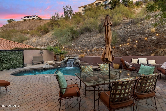 pool at dusk with pool water feature and a patio