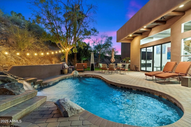 pool at dusk with a patio