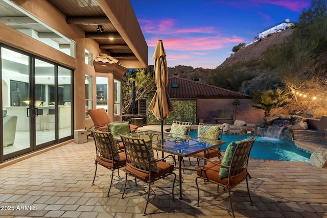 patio terrace at dusk featuring pool water feature