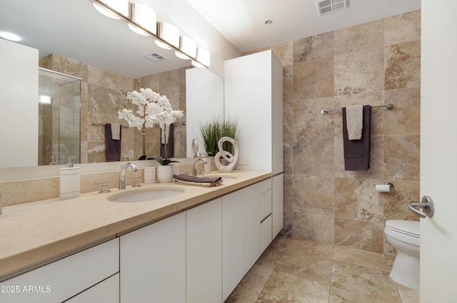 full bathroom with a stall shower, visible vents, tile walls, and vanity