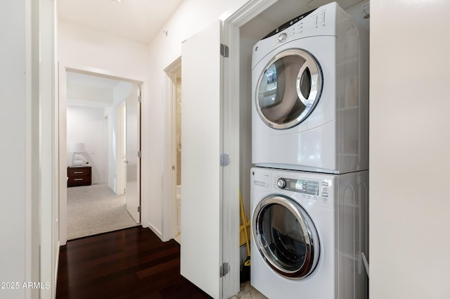 clothes washing area featuring laundry area, stacked washing maching and dryer, and wood finished floors