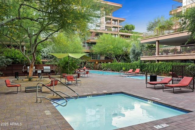 community pool with a patio area and fence