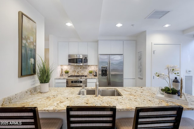 kitchen with a breakfast bar area, visible vents, stainless steel appliances, and a sink