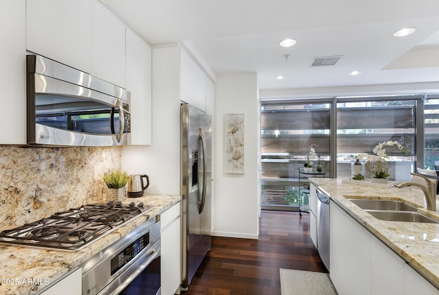 kitchen with dark wood-style floors, stainless steel appliances, visible vents, a sink, and modern cabinets