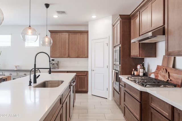 kitchen with appliances with stainless steel finishes, decorative light fixtures, and sink