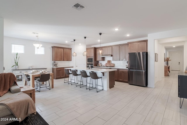 kitchen with a center island with sink, a breakfast bar, decorative light fixtures, and stainless steel appliances