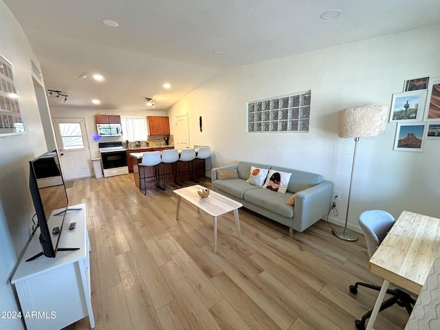 living room with lofted ceiling, light wood-style floors, and recessed lighting