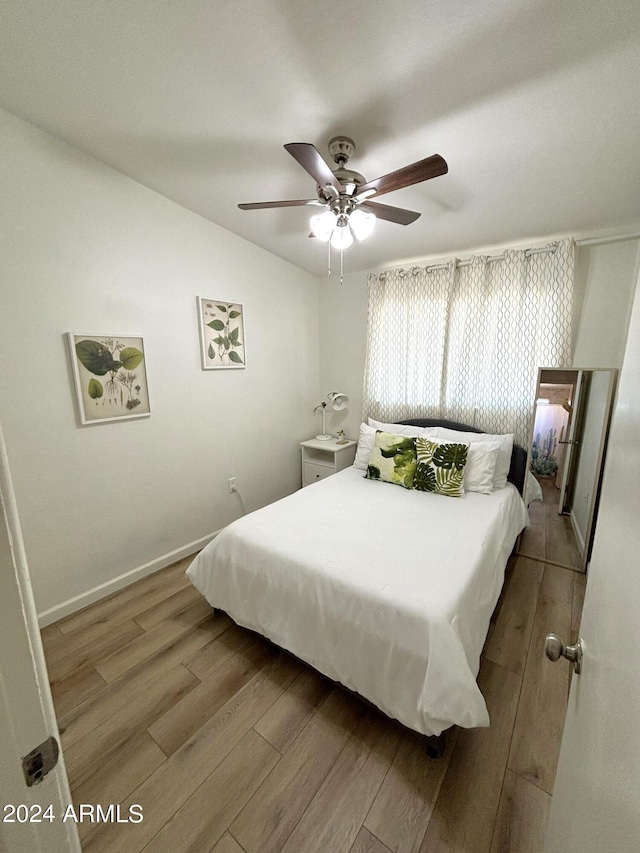 bedroom featuring ceiling fan, light wood finished floors, and baseboards