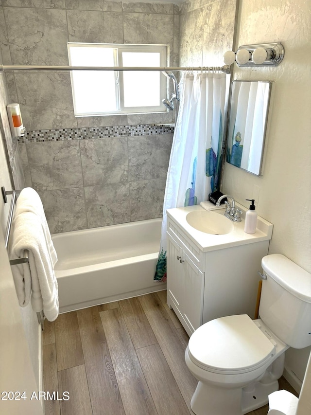 bathroom featuring toilet, shower / tub combo, wood finished floors, and vanity