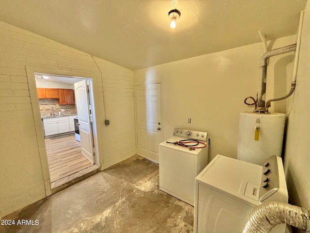 clothes washing area with washing machine and dryer, laundry area, brick wall, a sink, and water heater